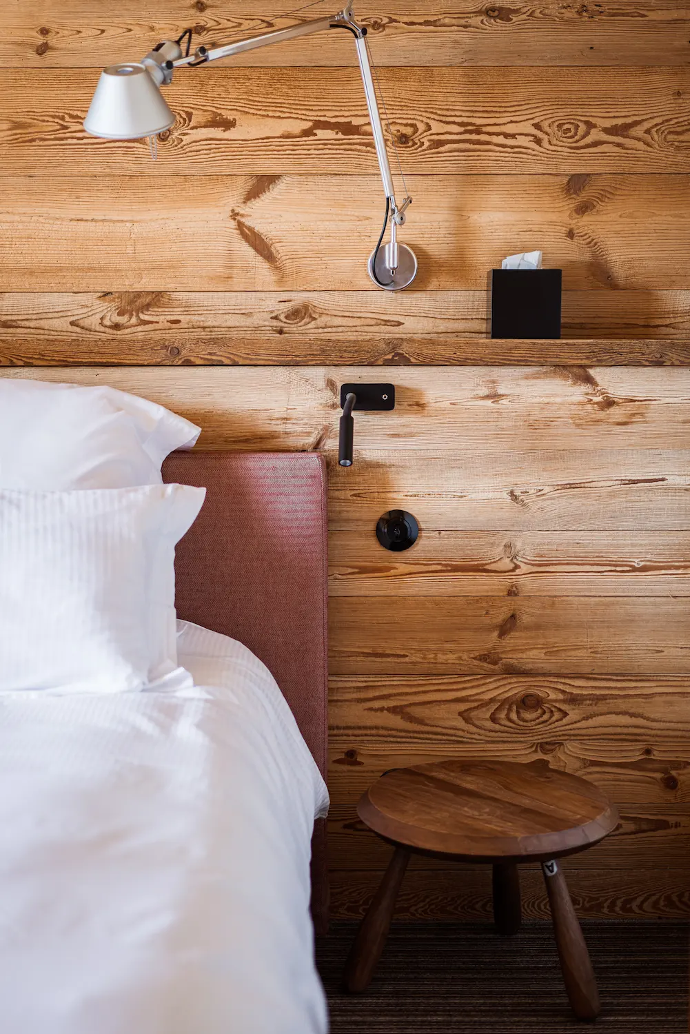 Chambre Vieux Bois – détail de la tête de lit en bois avec lampe de chevet et tabouret rond