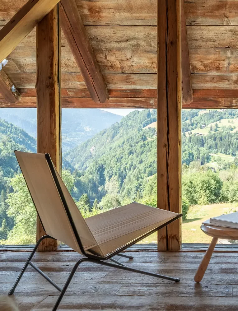 Vue du salon de lecture cosy de la Ferme du Passieu, avec fauteuils, bibliothèque et lumière naturelle.