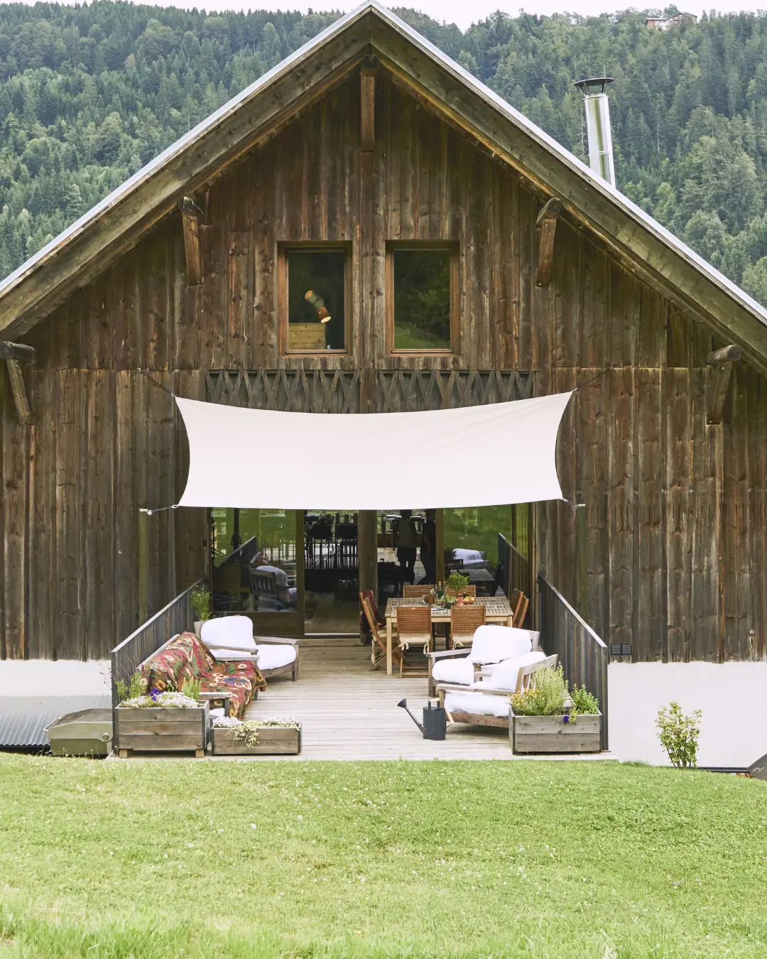 Façade du bâtiment en bois avec grande toile tendue au-dessus de la terrasse