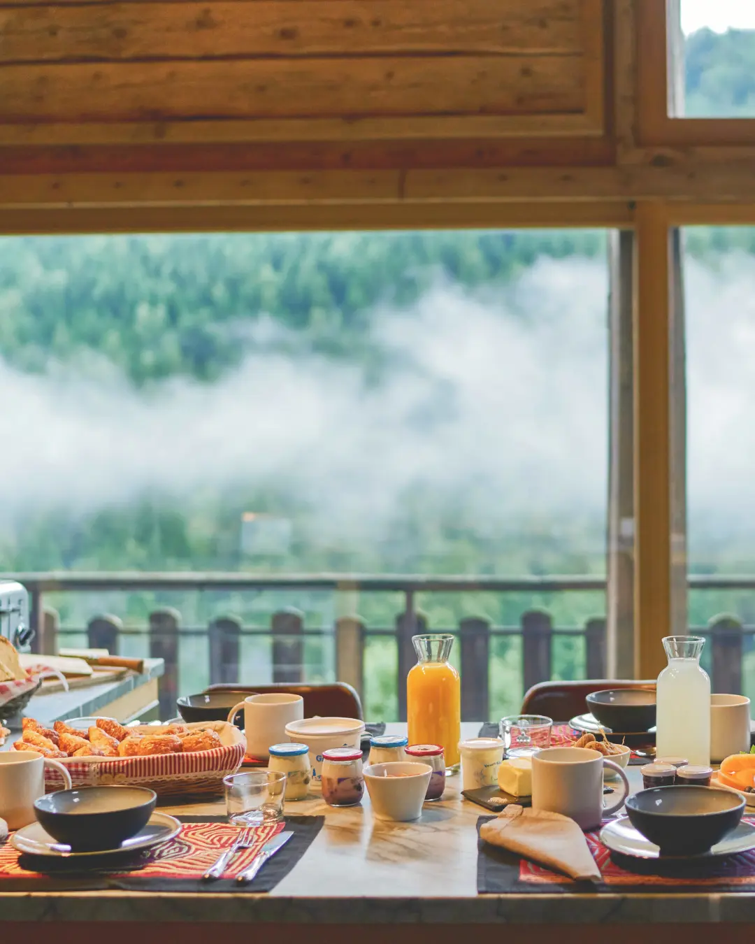Breakfast served on the terrace with pastries, coffee, and orange juice, with a view of the mountains