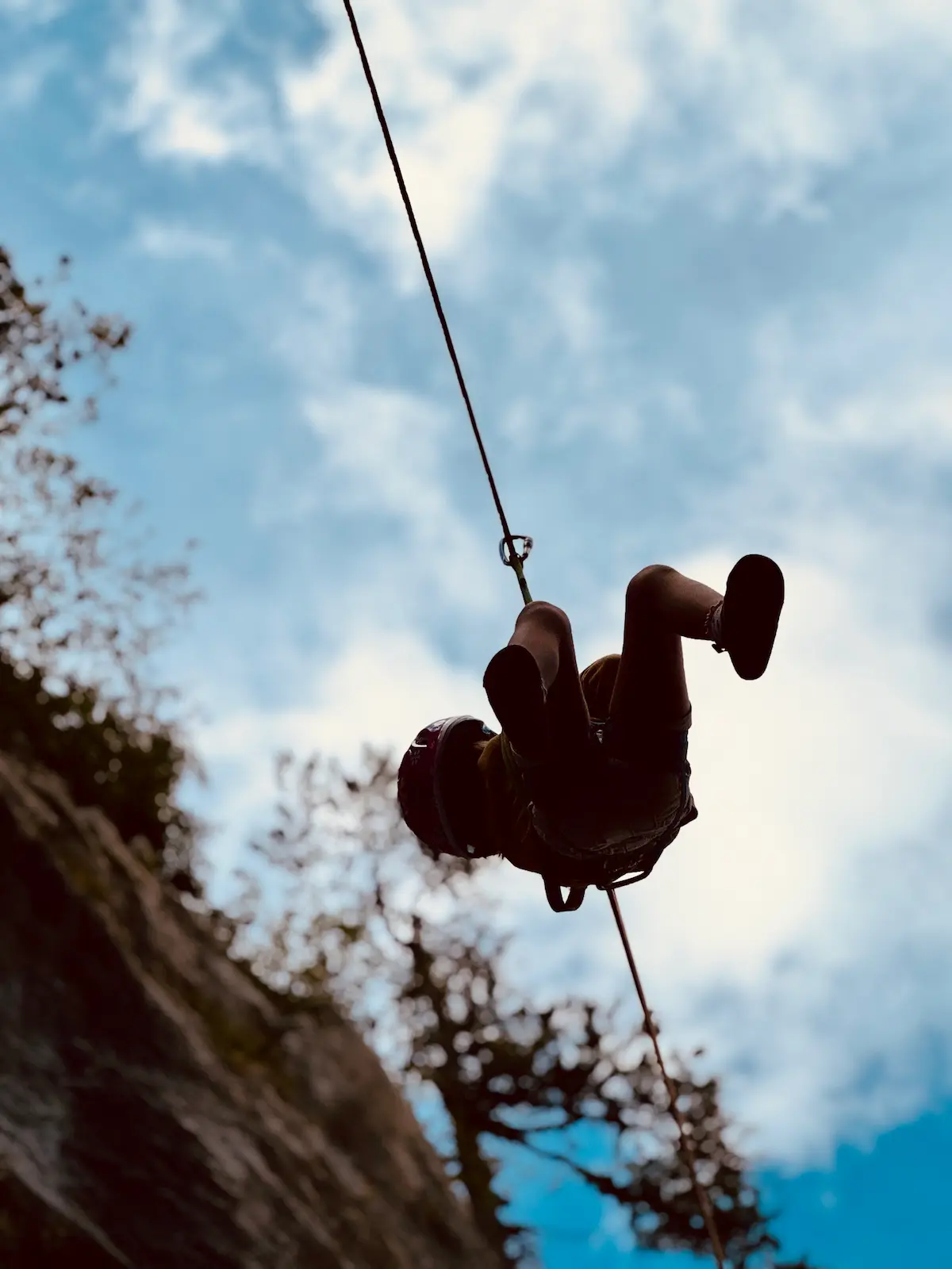 Vue en contre-plongée d'une paroi rocheuse avec corde d'escalade et ciel bleu