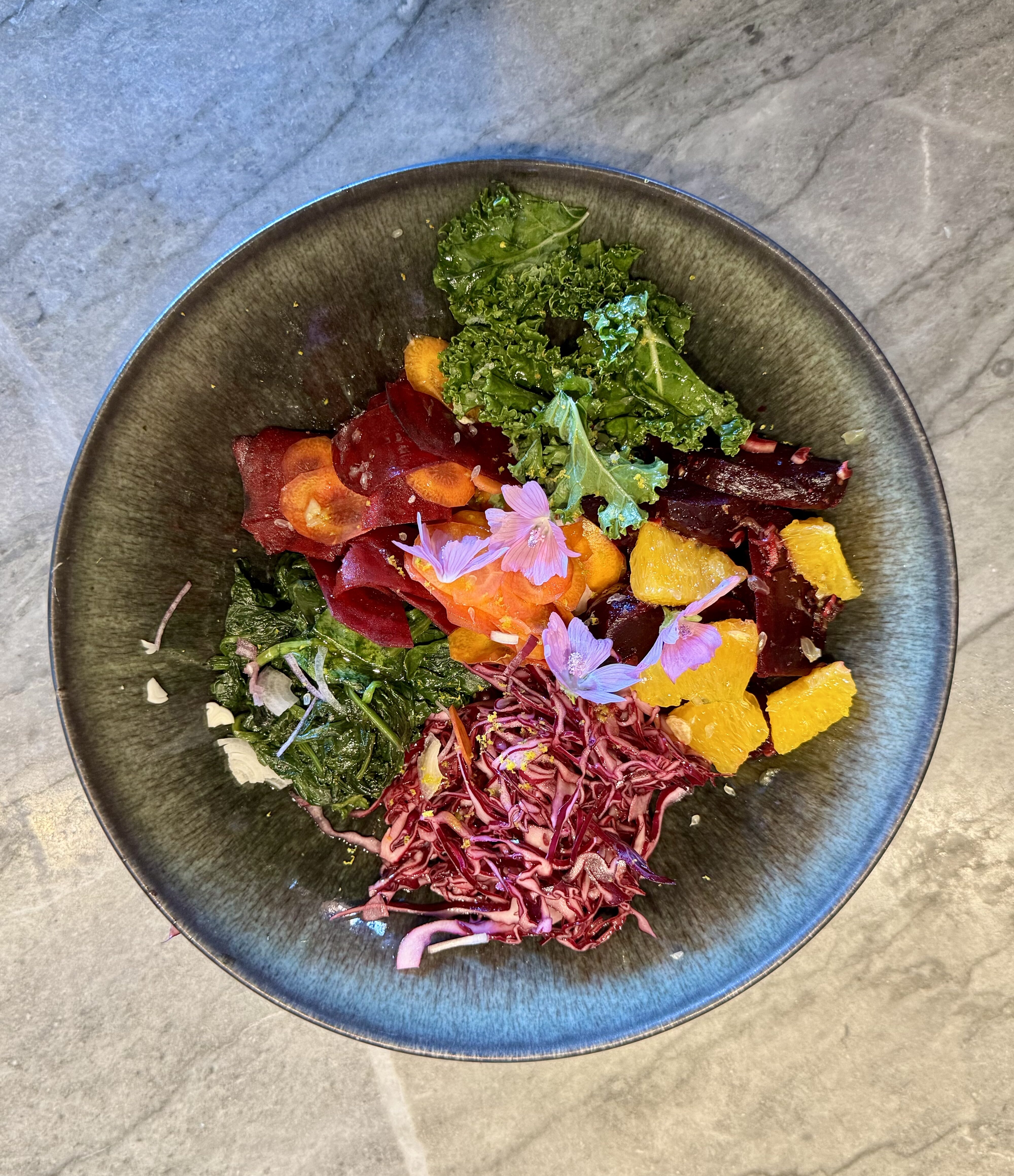 Assiette végétale colorée avec betterave, chou kale, agrumes et fleurs comestibles