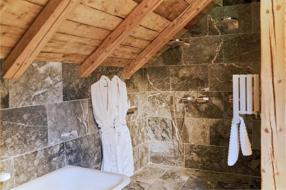 Suite Master – détail de la salle de bain en pierre avec peignoirs suspendus
