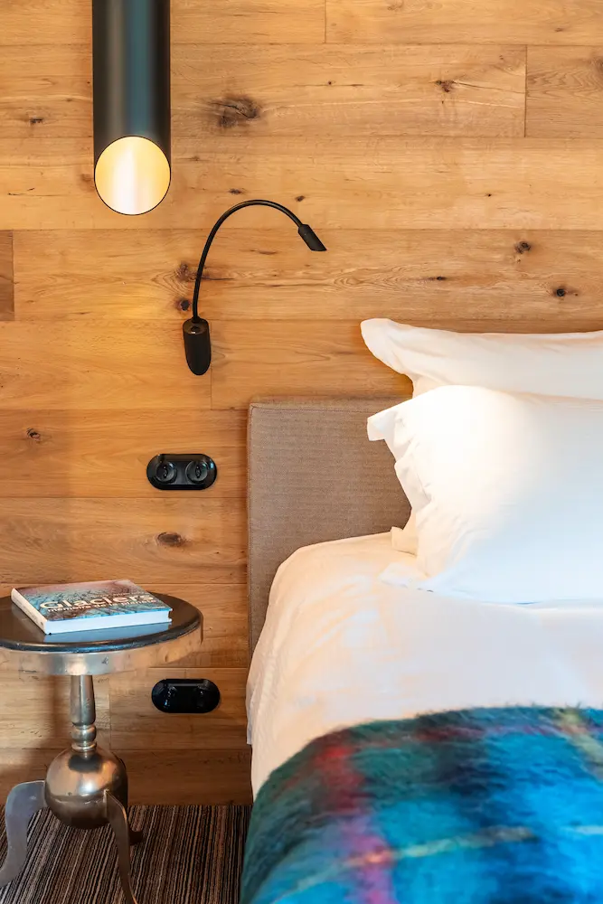 Chambre Chêne – détail de chevet avec liseuse, guéridon et livre