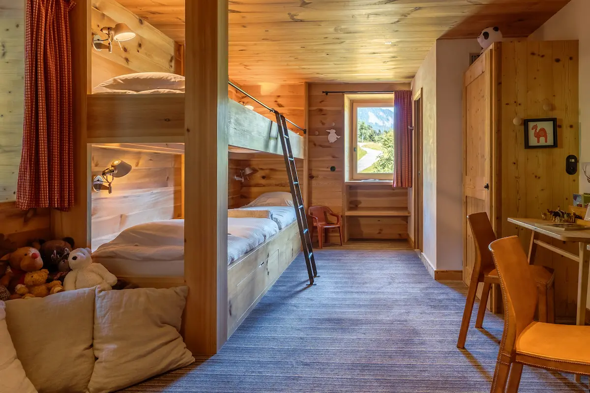 Chambre Dortoir – lits superposés en bois avec peluches et couloir vers coin bureau