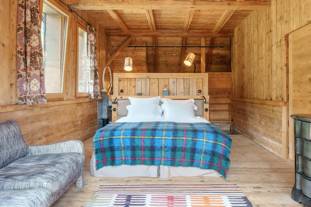 Suite Master – lit avec plaid tartan bleu sous charpente en bois apparente