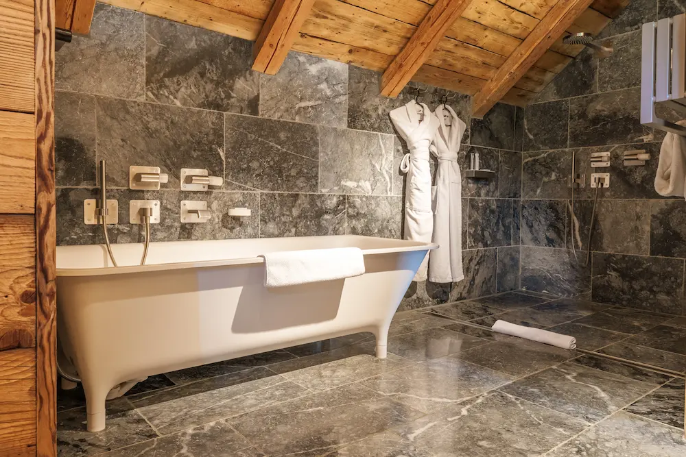 Suite Master – salle de bain avec baignoire îlot et murs en pierre grise