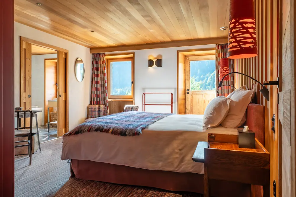 Chambre Red Cedar – vue d'ensemble du lit avec plaid tartan et suspensions rouges