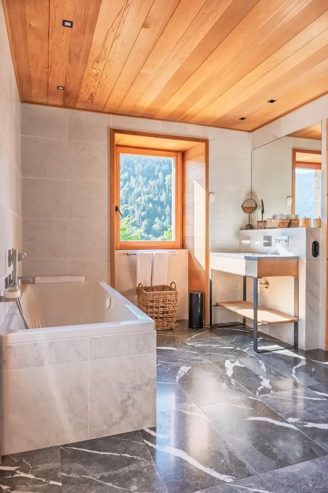 Chambre Red Cedar – salle de bain avec baignoire, fenêtre et sol en marbre gris