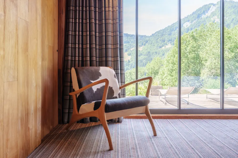 Chambre Teck – coin fauteuil devant la fenêtre avec vue sur les montagnes
